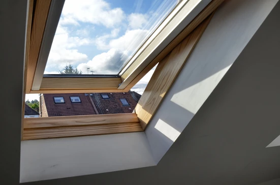 Int&eacute;rieur d'une chambre sous combles avec fen&ecirc;tre de toit ouverte en position ventilation