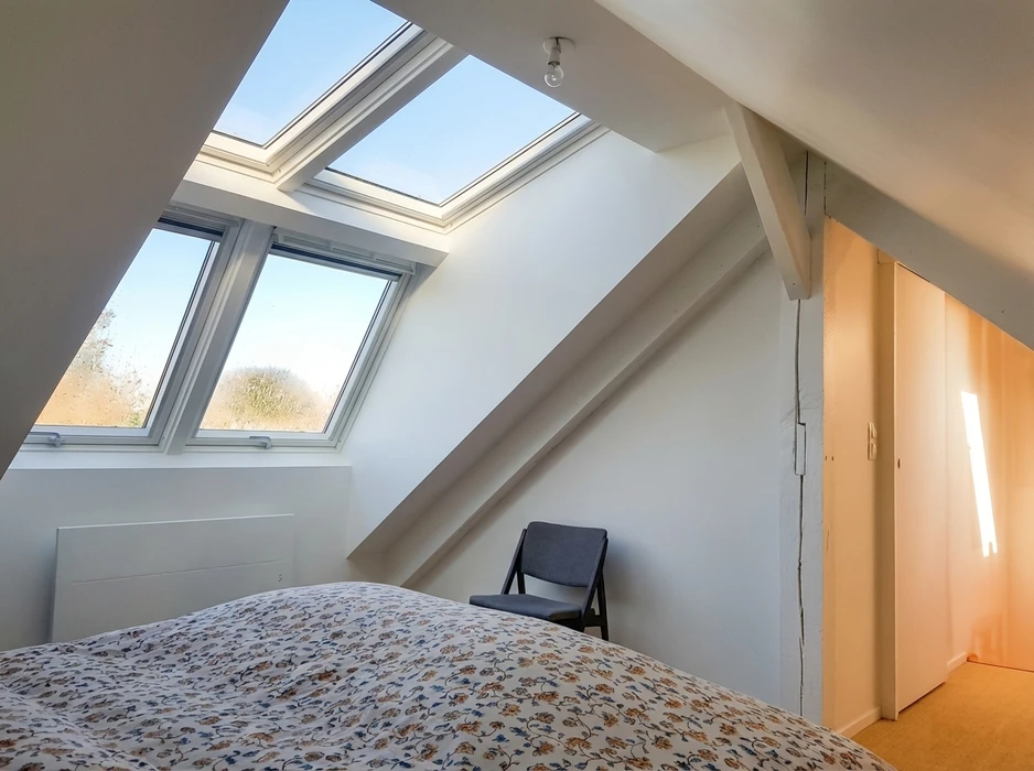 Chambre mansardée lumineuse avec fenêtres de toit VELUX combinées : un module vertical et un skylight ouvrant