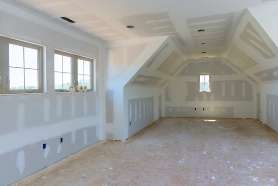 Int&eacute;rieur en cours de finition avec murs en plaques de pl&acirc;tre fra&icirc;chement pos&eacute;es, pr&ecirc;ts pour peinture