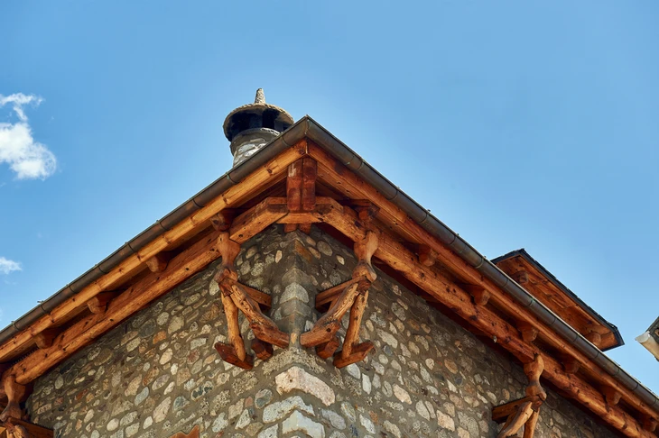 Extérieur d'une maison traditionnelle avec murs en pierre naturelle et charpente apparente en bois