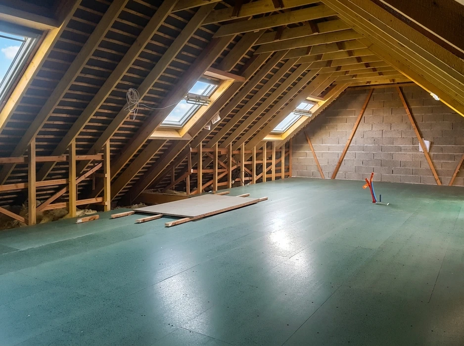 Grenier en cours d'aménagement, vide et spacieux, avec charpente en bois apparente, trois fenêtres de toit Velux