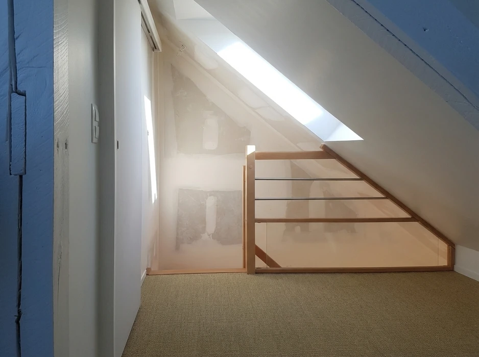 Combles aménagés en cours de rénovation, mur avec enduit arraché révélant la maçonnerie