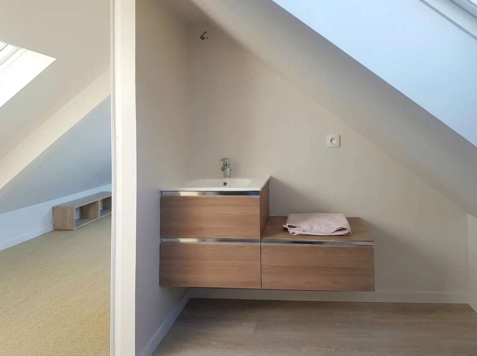 Grenier en cours d'aménagement, vide et spacieux, avec charpente en bois apparente, trois fenêtres de toit Velux
