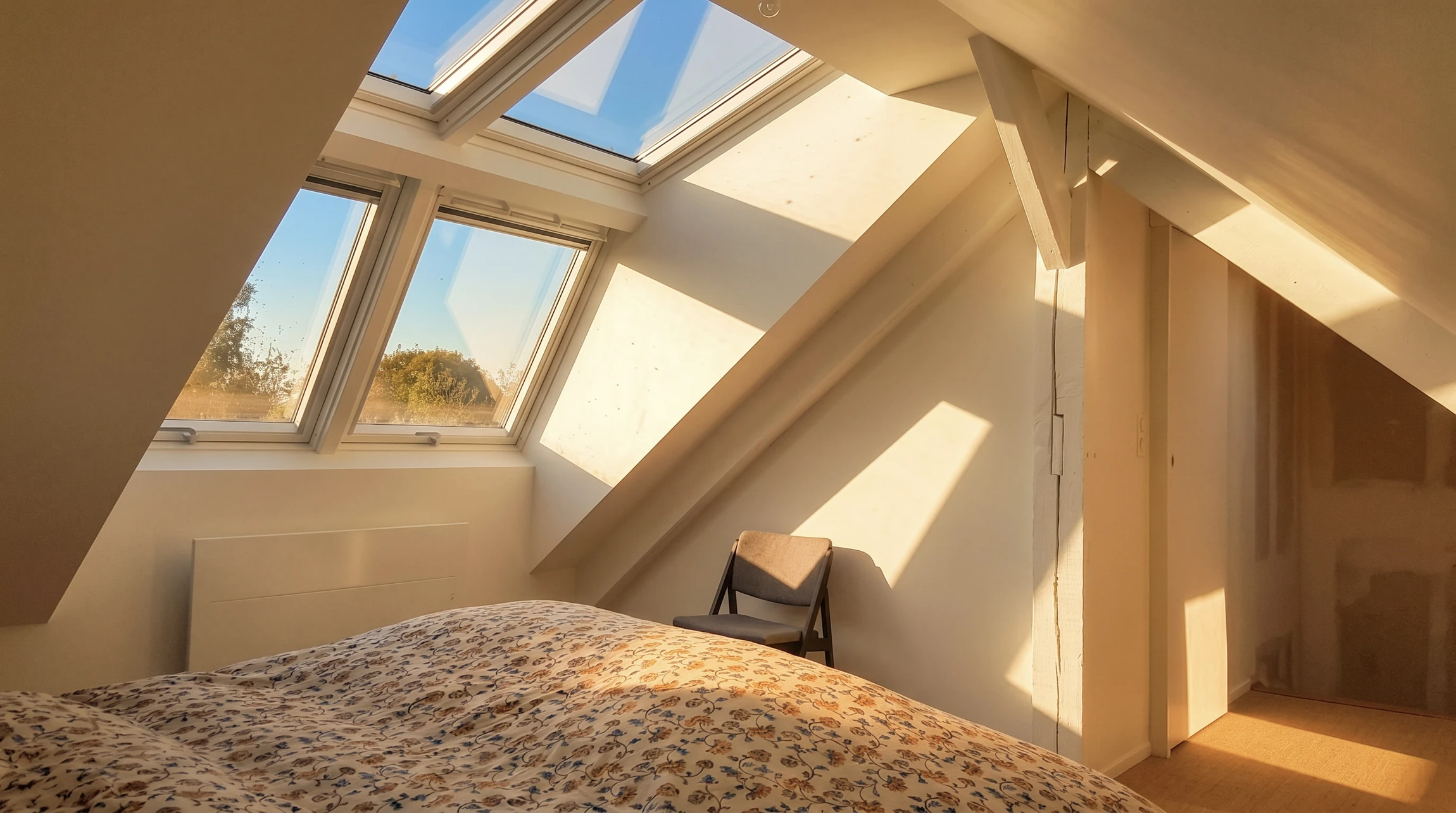 Scène extérieure de toiture en tuiles avec fenêtre de toit ouverte équipée d'un volet roulant solaire déployé