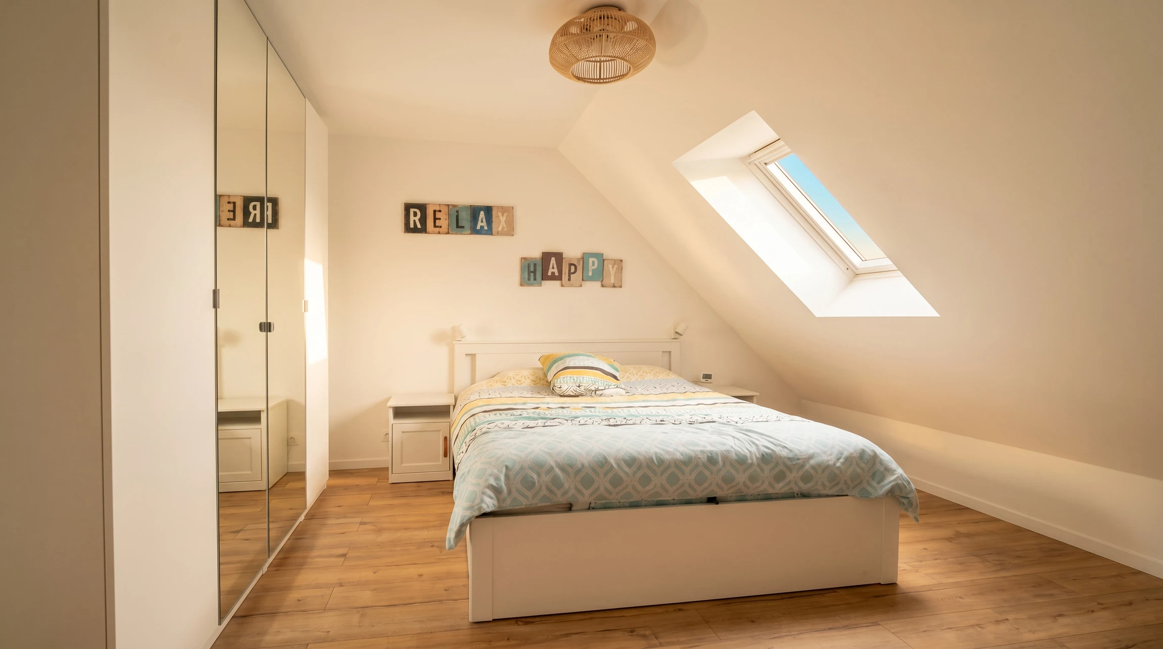 Intérieur d'un comble aménagé avec charpente apparente en bois massif, parquet au sol et radiateurs blancs sous fenêtres